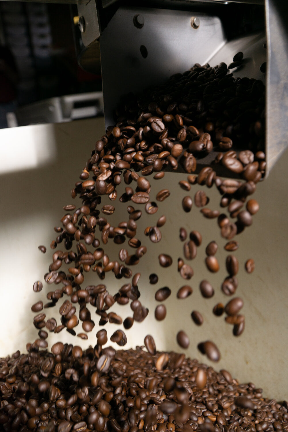 Freshly roasted coffee beans being poured from a roaster into a cooling tray at Cottonwood Coffee, capturing the process of creating high-quality coffee.