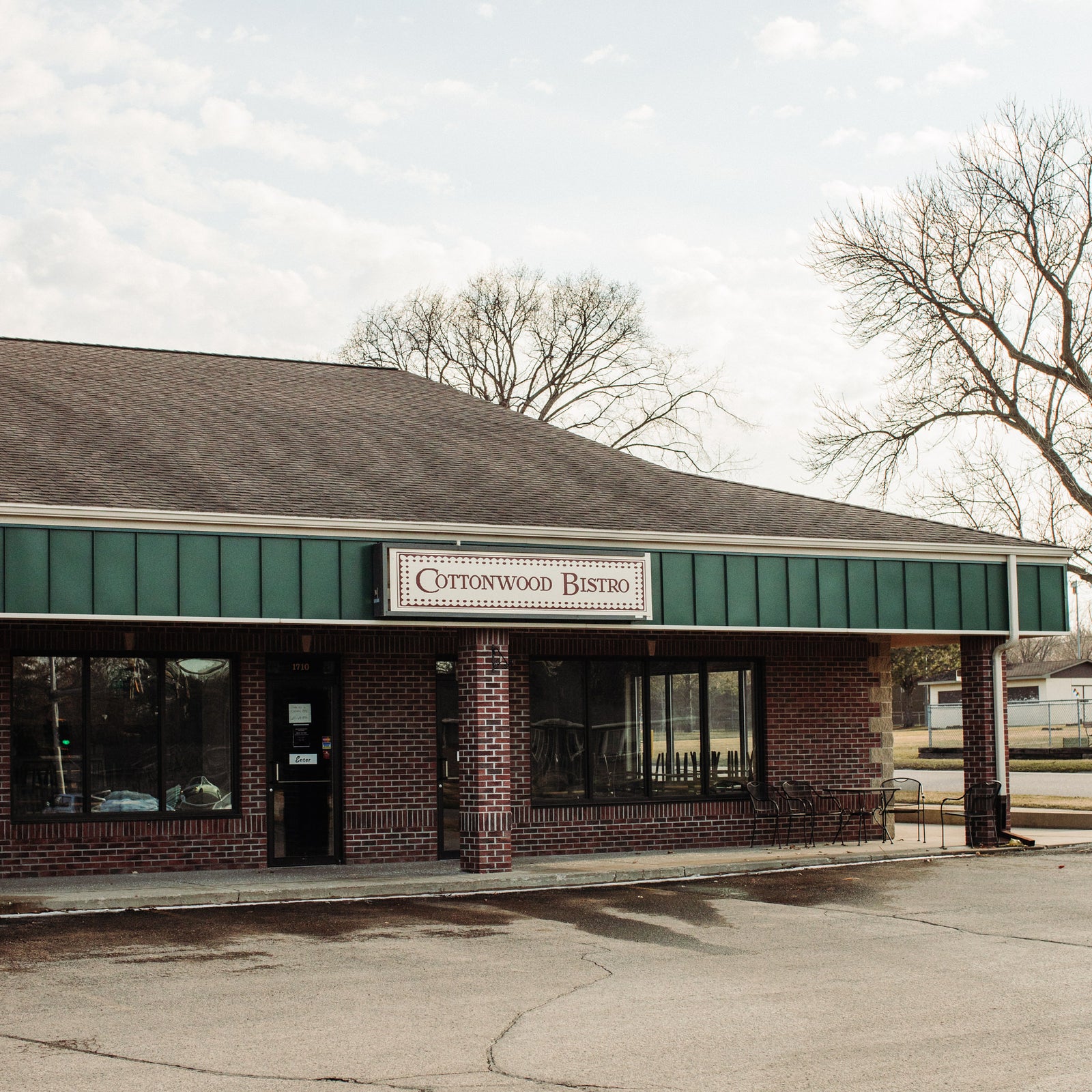 Exterior of Cottonwood Bistro, featuring a welcoming brick building and green accents, located in a quiet neighborhood.