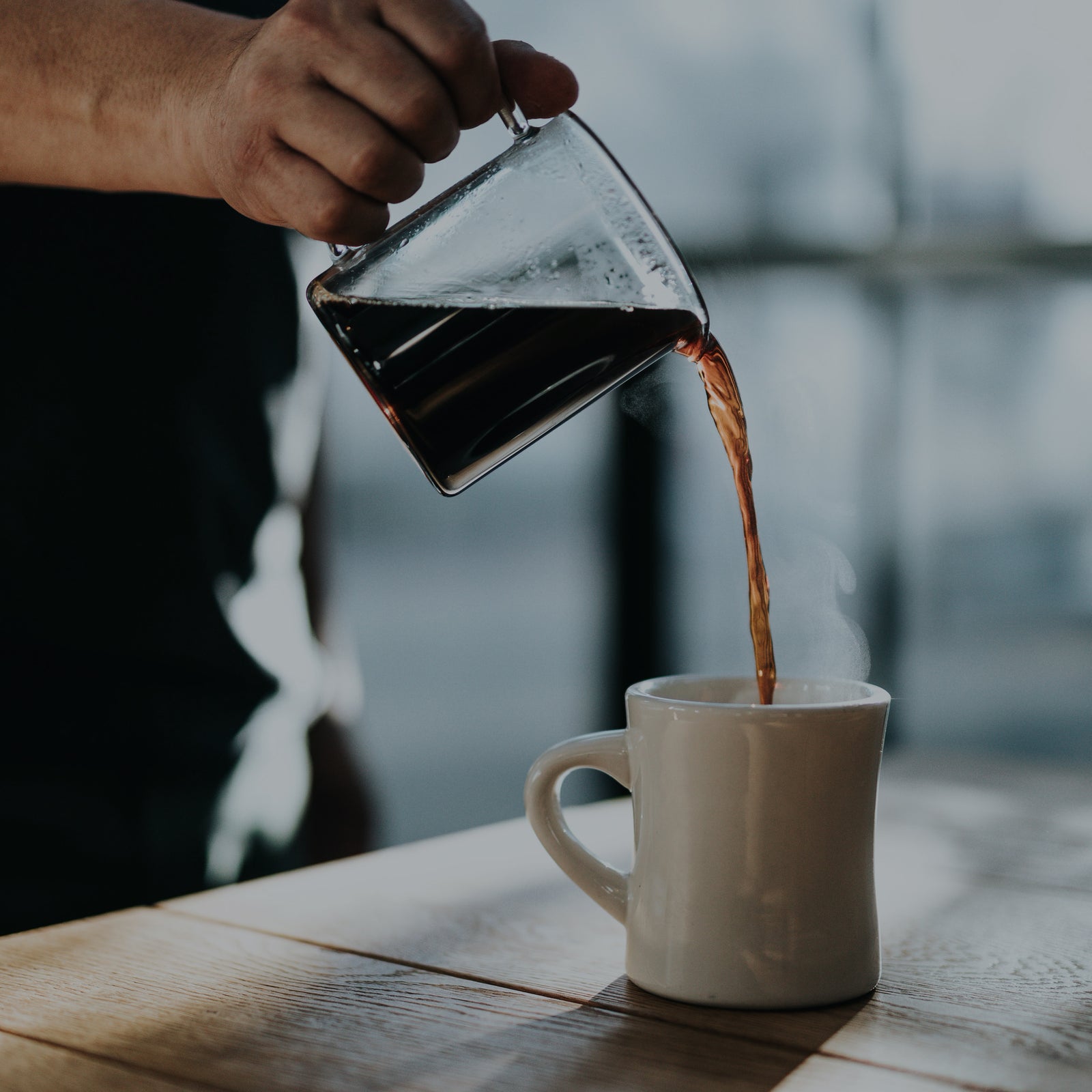 Hot coffee being poured into a white ceramic mug at Cottonwood Coffee, showcasing the warmth and craftsmanship of the brewing process.