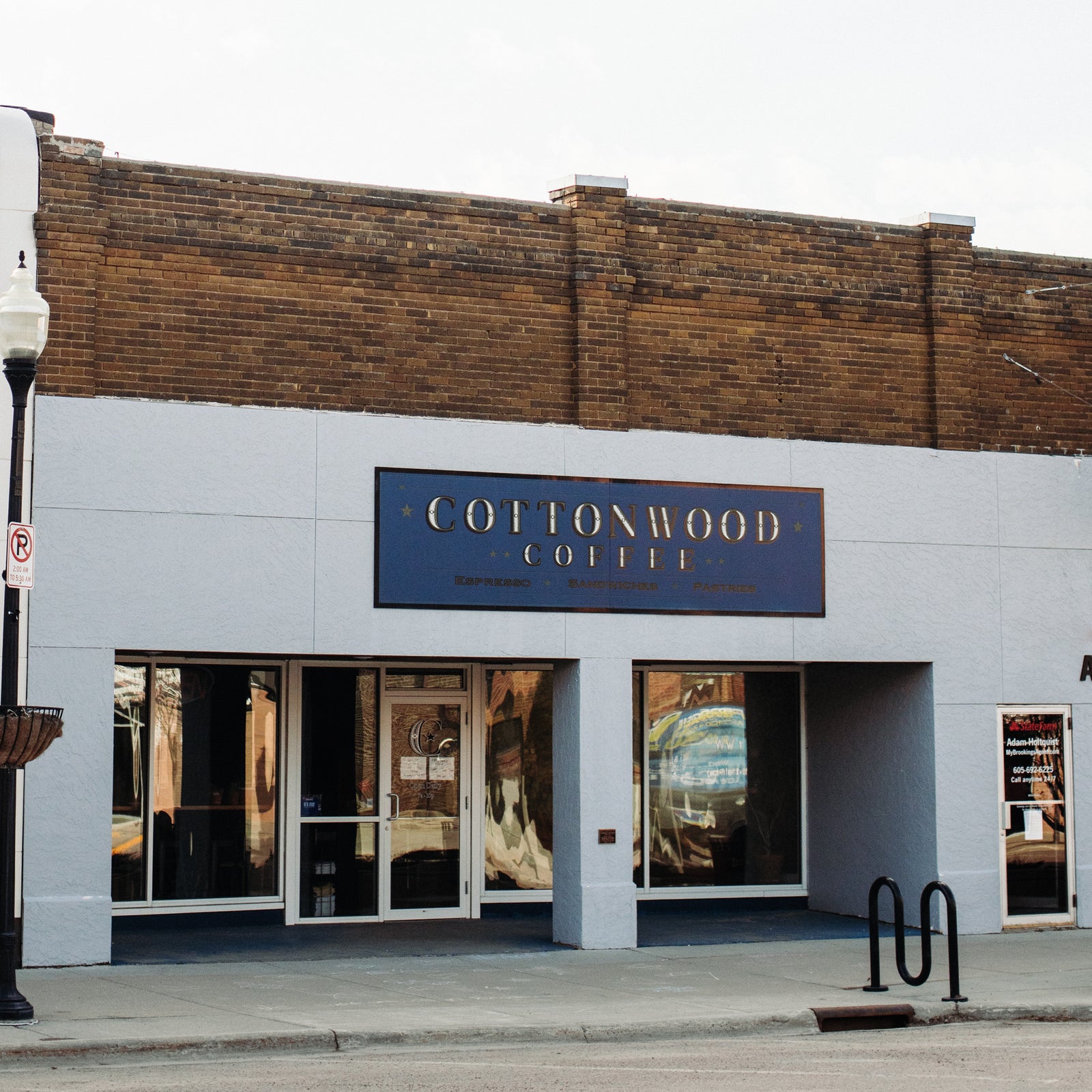 The storefront of Cottonwood Coffee, featuring a modern sign and large windows, located in a charming brick building on Main Street.