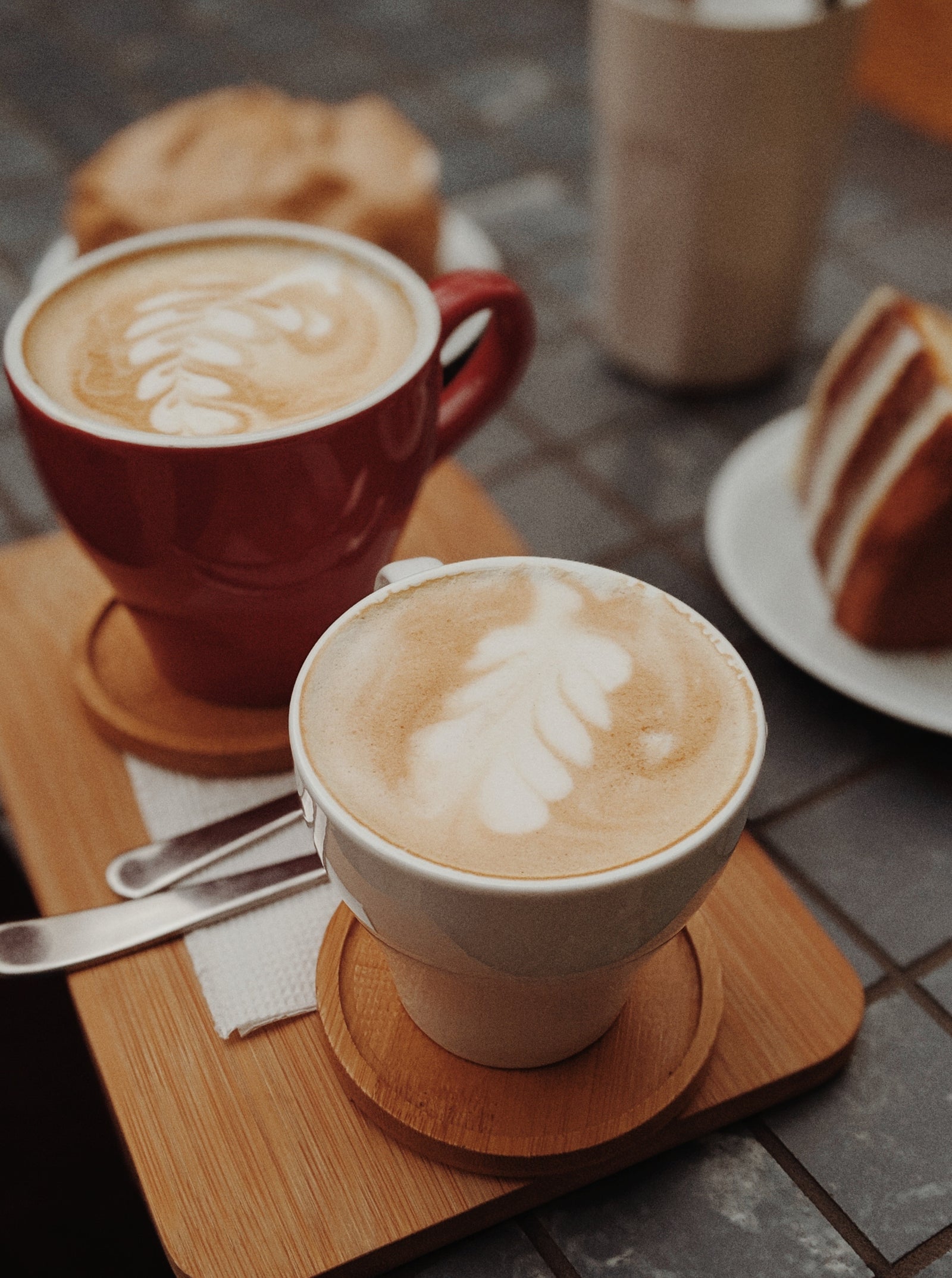 Two lattes with beautiful latte art served in red and white mugs at Cottonwood Coffee, paired with pastries for a cozy café experience.